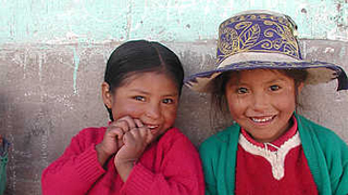 zwei Mädchen; das rechte trägt einen Hut